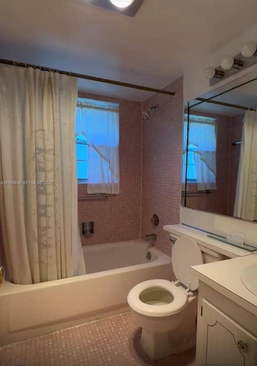 573 Durham U, #573, Deerfield Beach, FL 33442 Bathroom featuring a tile-surround bathtub, vanity with a countertop basin, wall-mounted mirror, and multi-bulb light fixture