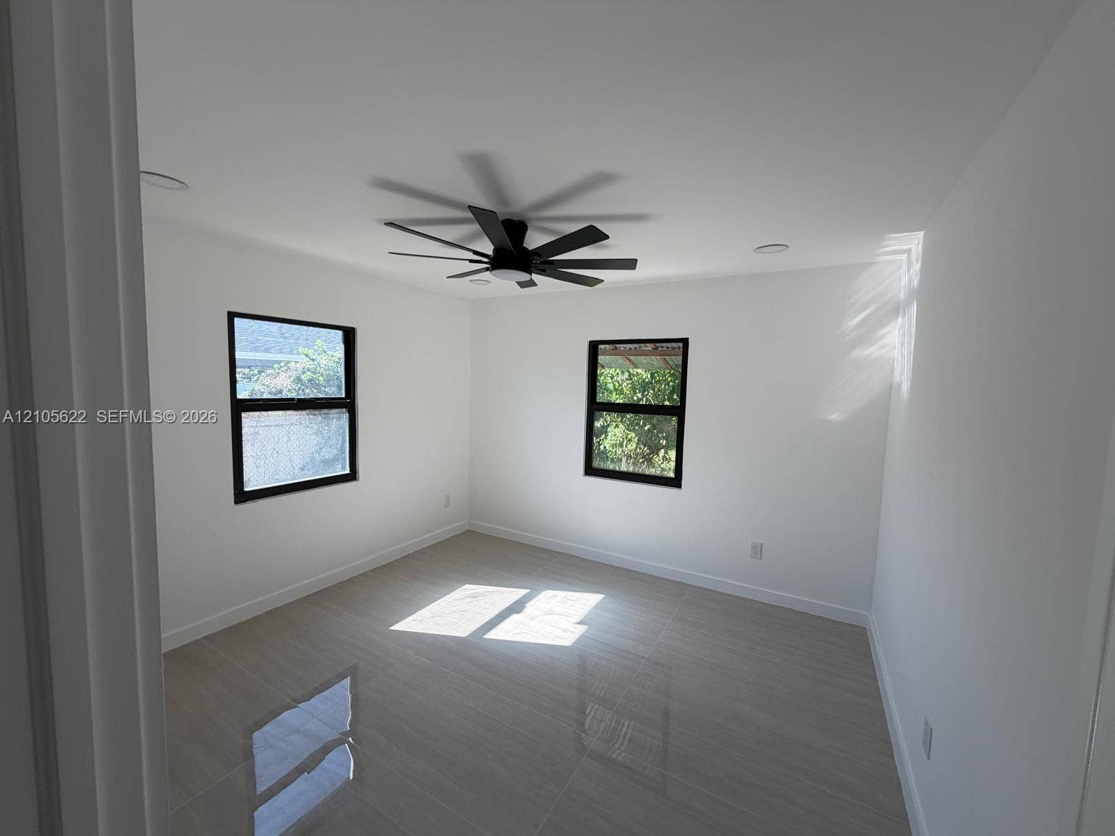 9728 Little River Drive, Miami, FL 33147 Interior space featuring neutral wall paint, polished tile flooring, recessed lighting, and a modern black ceiling fan with dual-pane windows framed in black