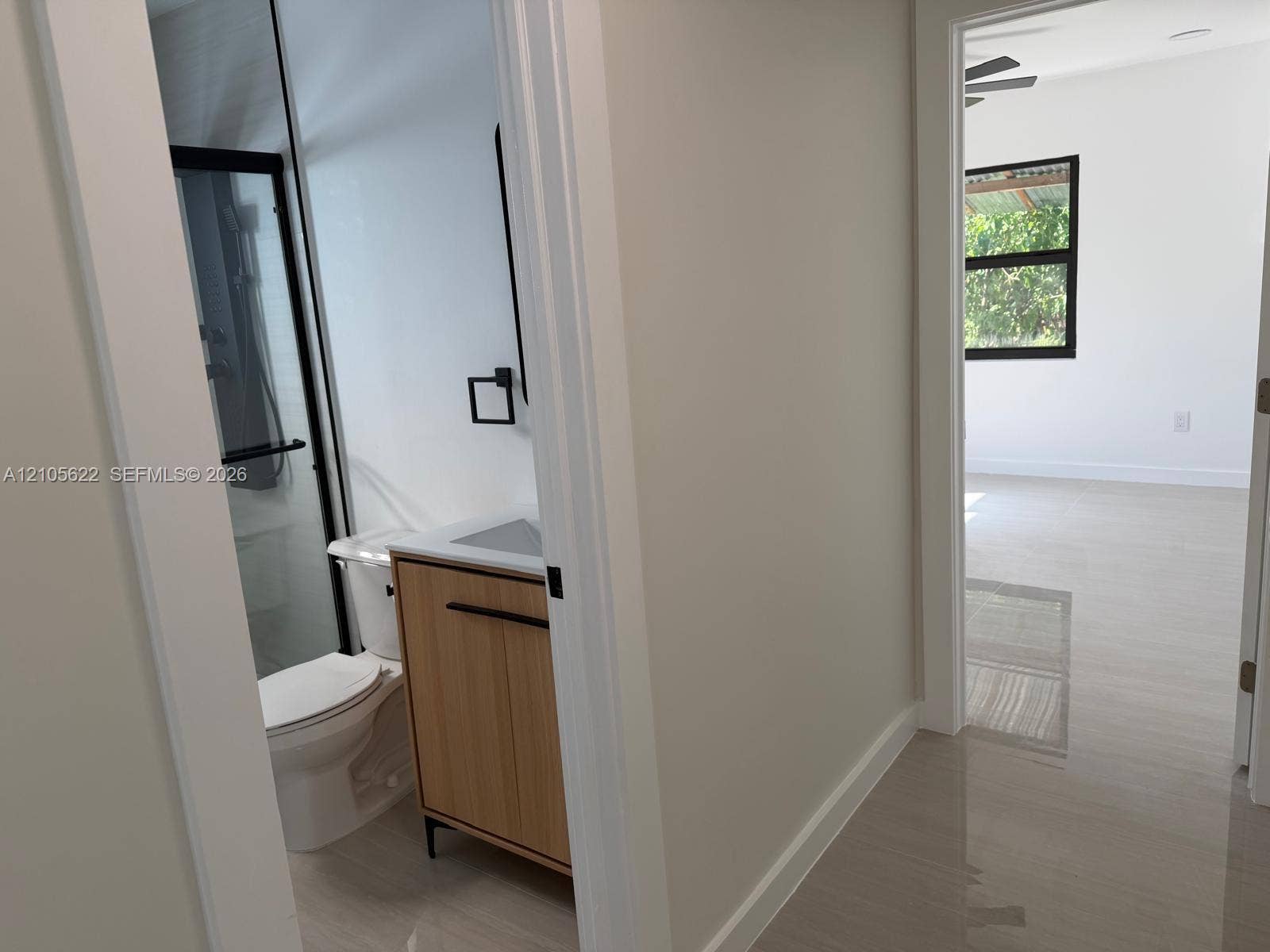 9728 Little River Drive, Miami, FL 33147 Bathroom featuring a wood-finish vanity with a rectangular sink, matte black hardware, and a glass-enclosed shower with black framing