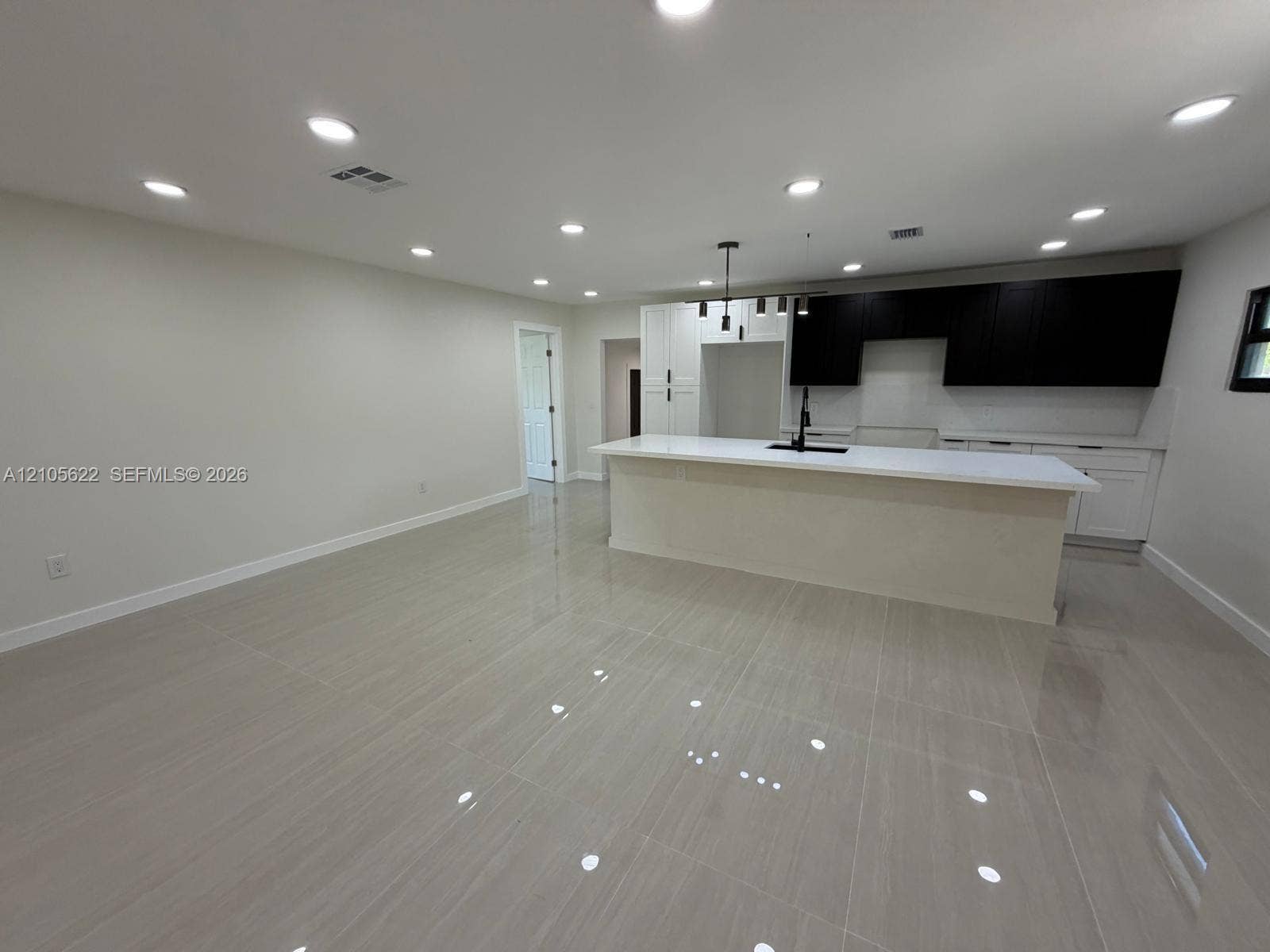 9728 Little River Drive, Miami, FL 33147 Open-concept kitchen featuring two-tone cabinetry, a central island with a stone-finish countertop, recessed ceiling lighting, and large-format tile flooring