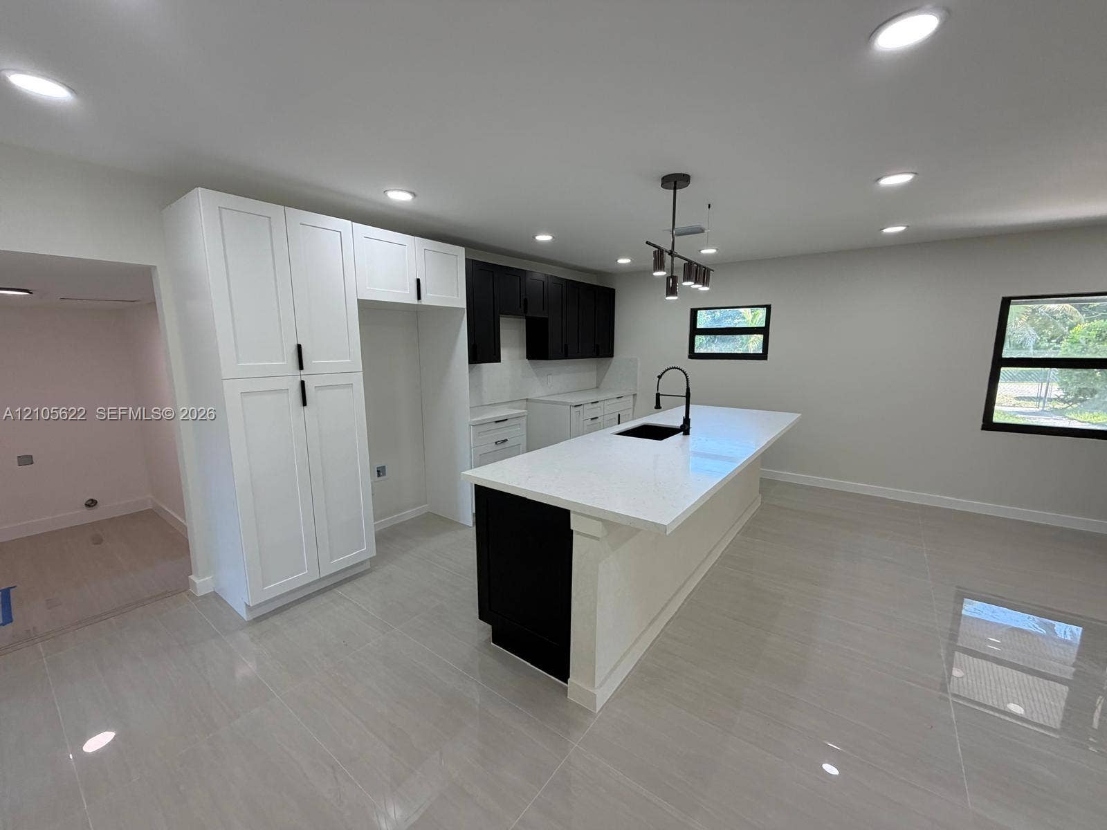 9728 Little River Drive, Miami, FL 33147 Kitchen featuring high-contrast cabinetry, an expansive center island with a stone countertop, an integrated undermount sink with a matte black faucet, recessed lighting, and large-format tile flooring