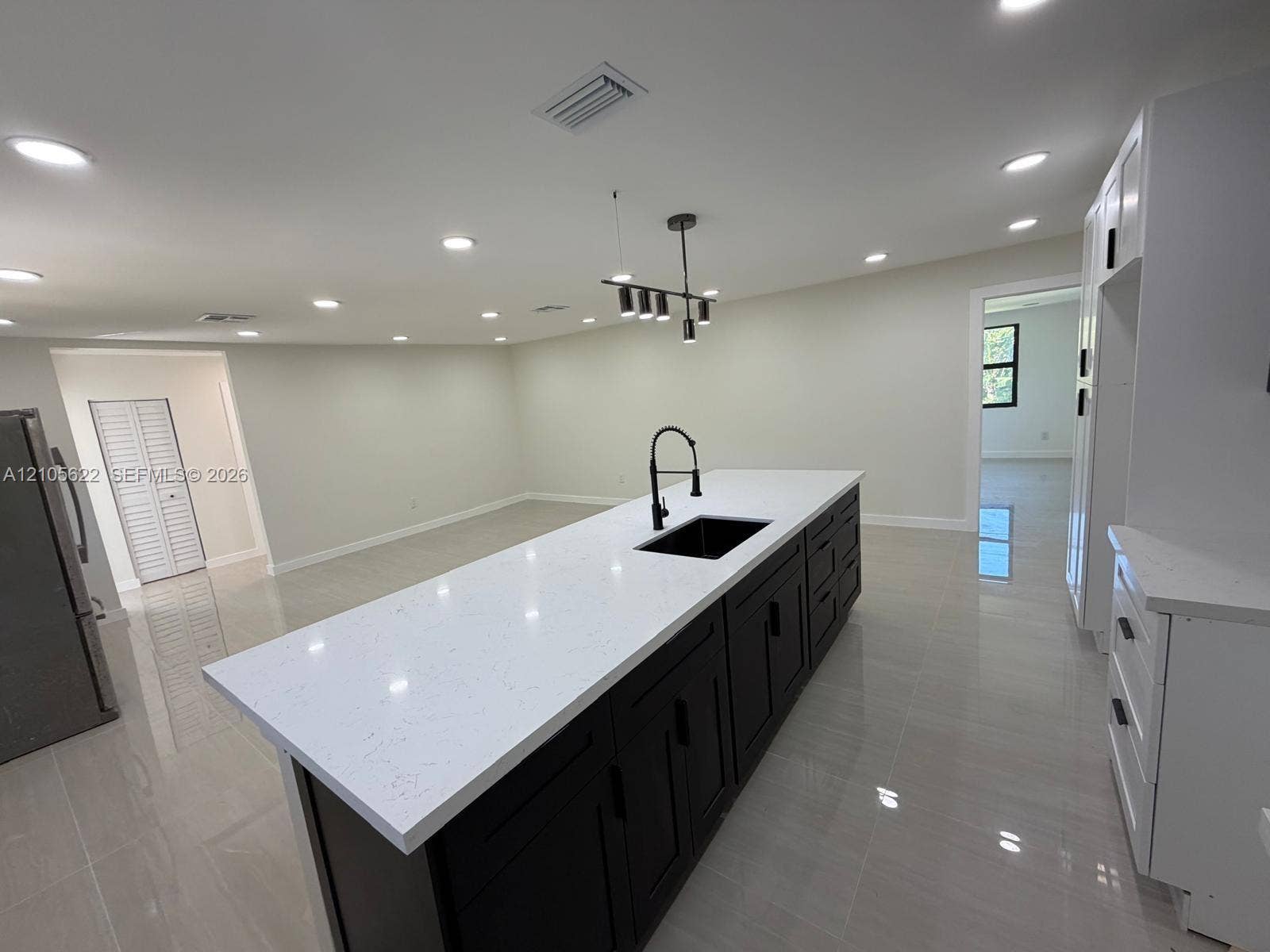 9728 Little River Drive, Miami, FL 33147 Kitchen island featuring dark cabinetry, quartz countertops, a recessed sink with a high-arch pull-down faucet, and overhead pendant lighting, complemented by polished tile flooring and recessed ceiling lights
