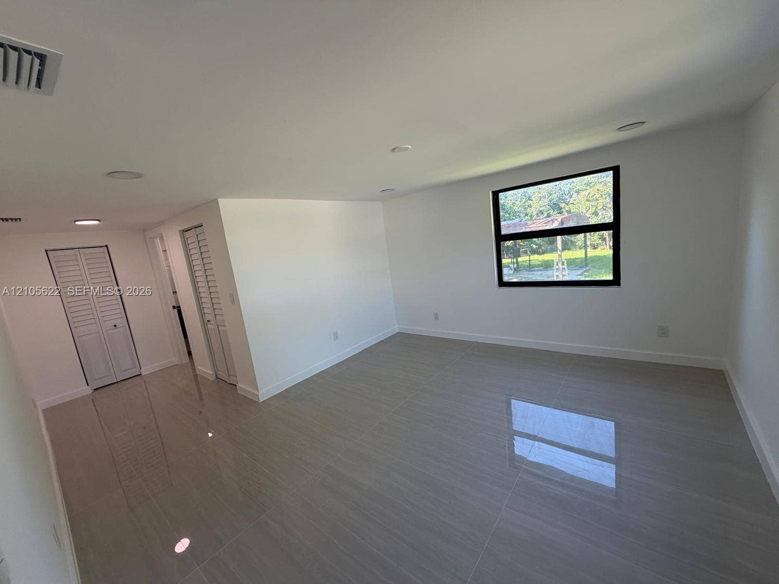 9728 Little River Drive, Miami, FL 33147 Large-format tile flooring, recessed ceiling lighting, louvered bi-fold closet doors, and black-frame window