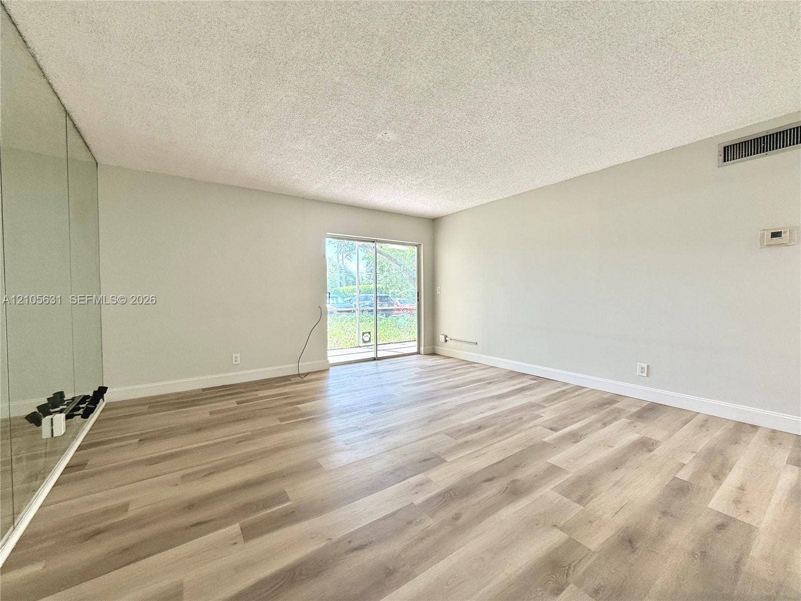 610 NW 13th Street, #0140, Boca Raton, FL 33486 Living space featuring wood-finish flooring, floor-to-ceiling mirrored walls, and sliding glass doors