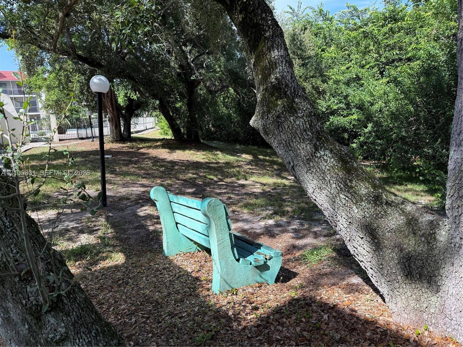 610 NW 13th Street, #0140, Boca Raton, FL 33486 Outdoor grounds featuring mature trees, a permanent stone bench, and a standalone post-mounted globe light