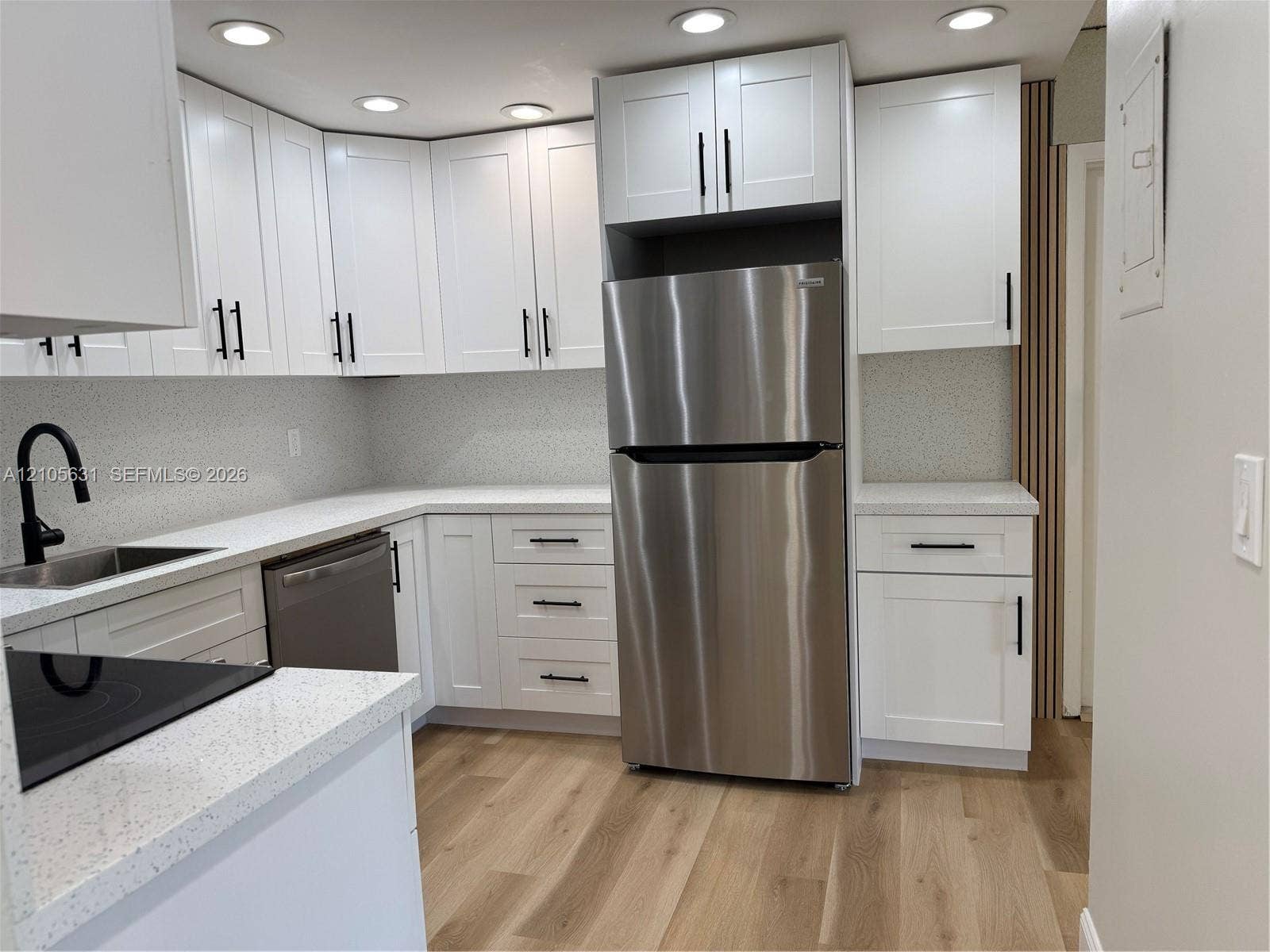 610 NW 13th Street, #0140, Boca Raton, FL 33486 Kitchen featuring white shaker-style cabinetry, quartz countertops, stainless steel appliances, matte black hardware, and wood-finish flooring