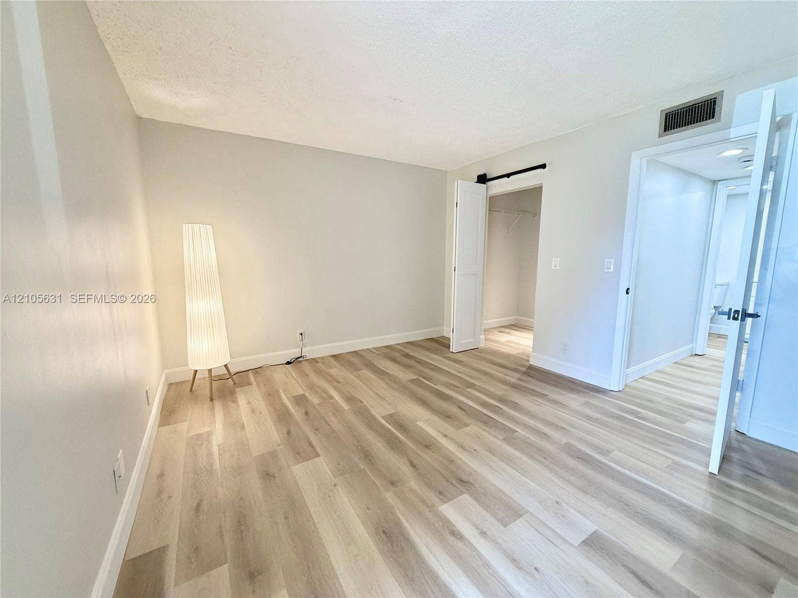 610 NW 13th Street, #0140, Boca Raton, FL 33486 Room featuring wood-finish flooring, a sliding barn door, and a built-in closet