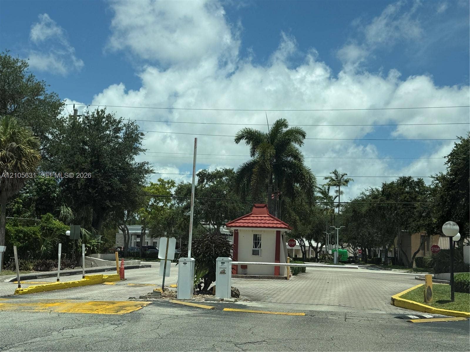 610 NW 13th Street, #0140, Boca Raton, FL 33486 Gated entry featuring a controlled-access barrier arm, guard house with a tile roof, and paved roadways