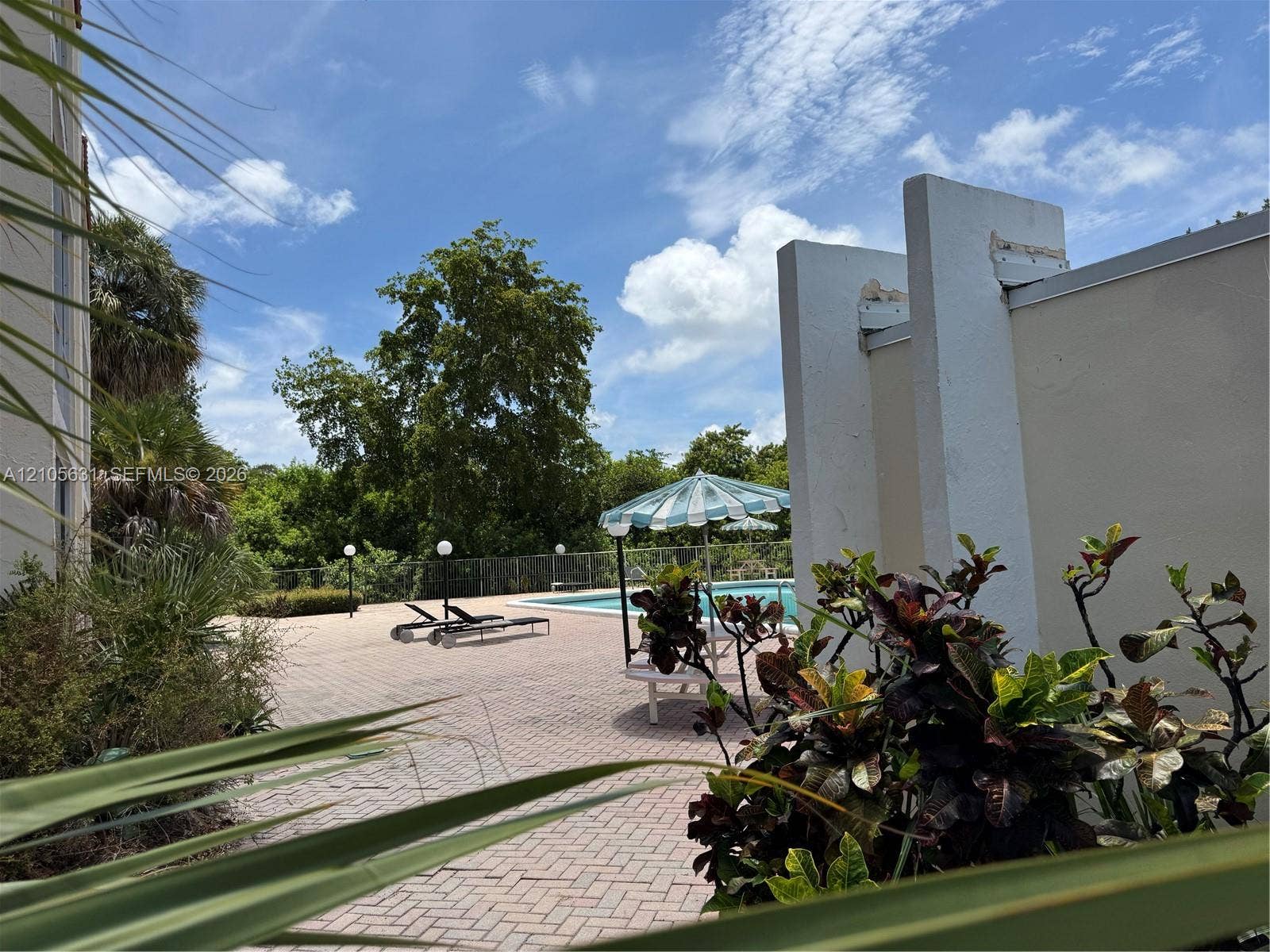 610 NW 13th Street, #0140, Boca Raton, FL 33486 Outdoor pool area featuring a paved deck, perimeter fencing, and mature landscaping