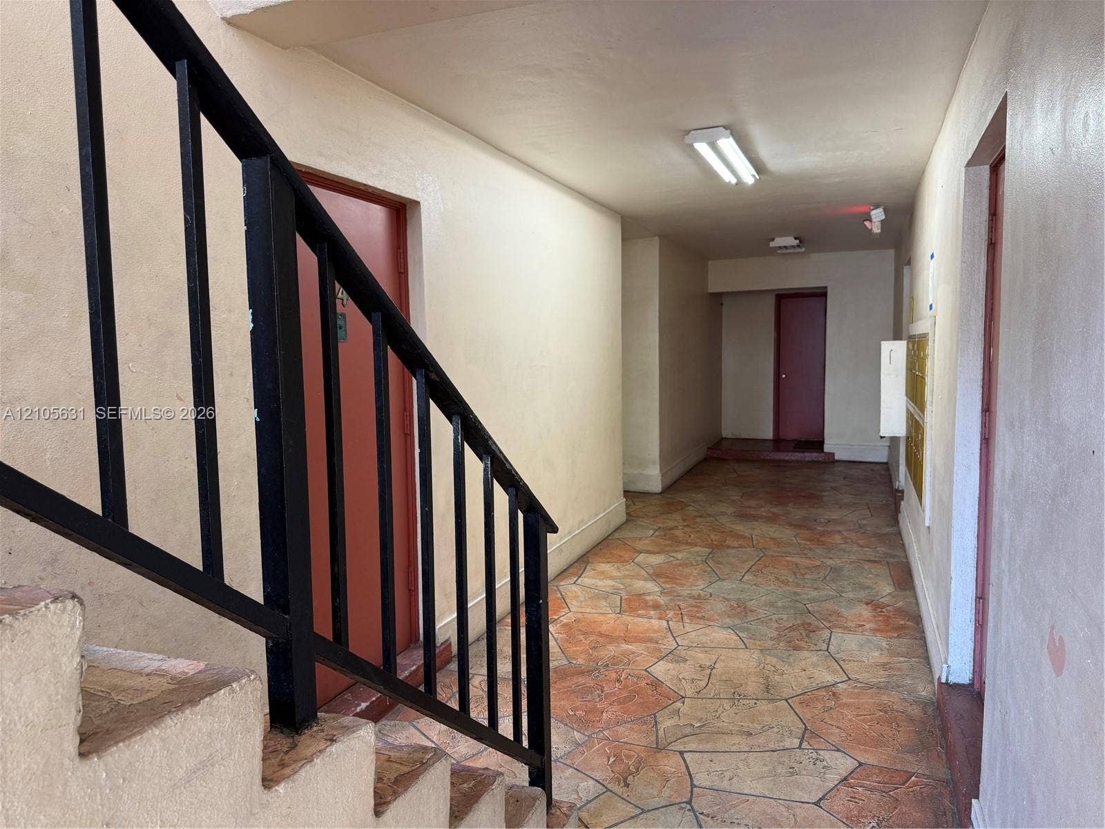 610 NW 13th Street, #0140, Boca Raton, FL 33486 Interior corridor featuring stone-patterned tile flooring, black metal handrails, and built-in mail receptacles