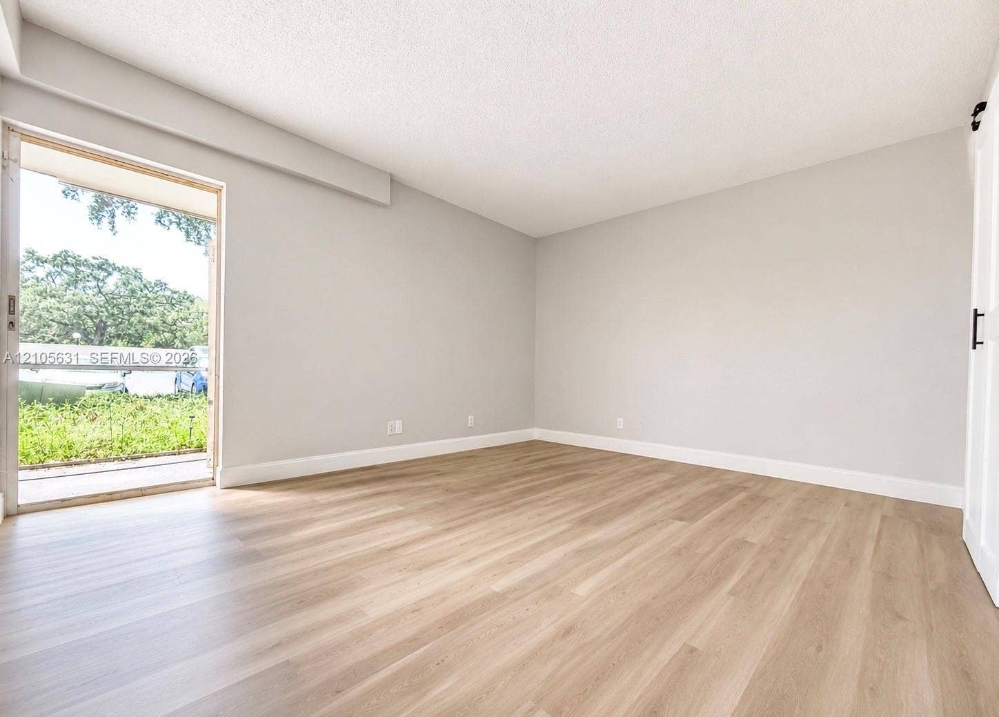 610 NW 13th Street, #0140, Boca Raton, FL 33486 Neutral-toned interior featuring wood-finish flooring, sliding glass door, and a white interior barn door