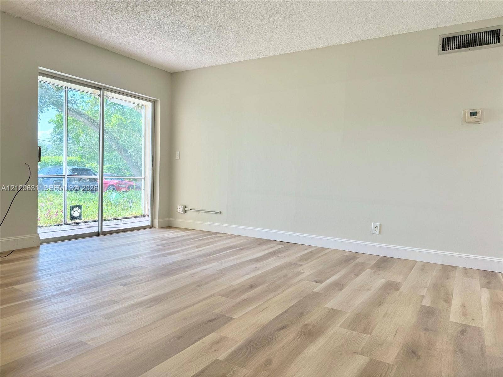 610 NW 13th Street, #0140, Boca Raton, FL 33486 Interior room featuring wood-finish flooring, textured ceiling, and sliding glass door