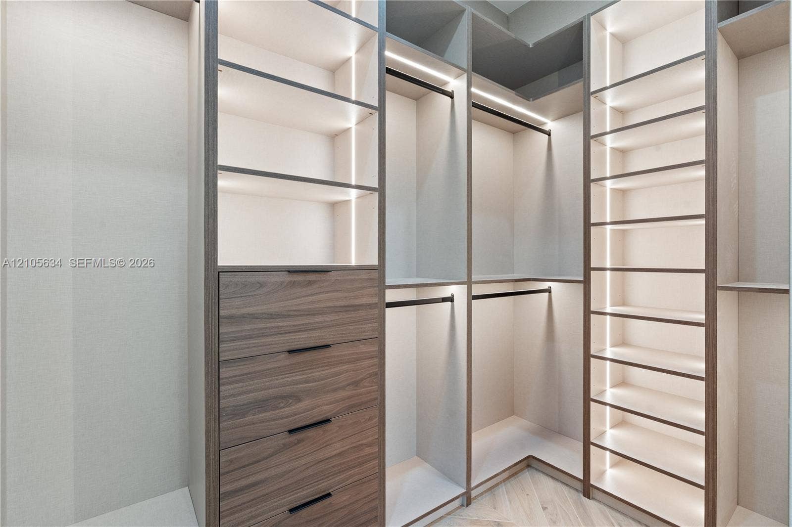 623 NE 16th Terrace, Fort Lauderdale, FL 33304 Custom floor-to-ceiling built-in cabinetry featuring wood-finish drawer fronts, integrated linear vertical lighting, adjustable open shelving, and matte black hardware