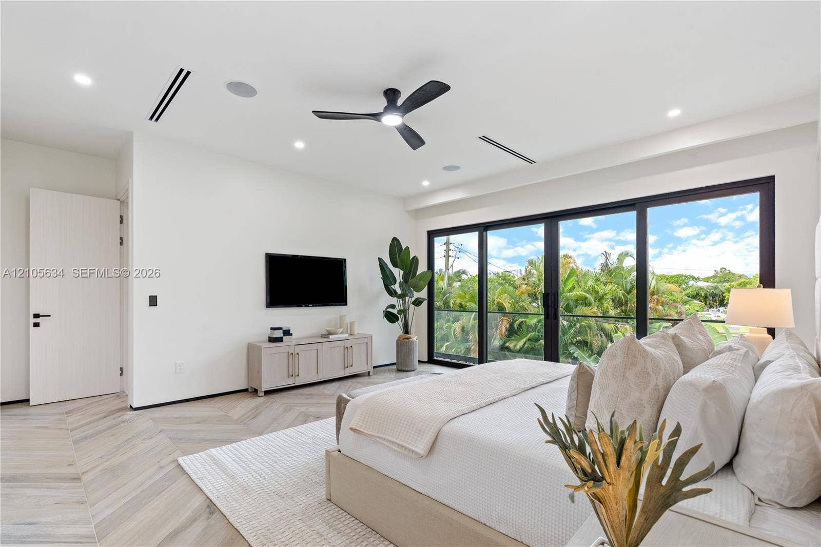 623 NE 16th Terrace, Fort Lauderdale, FL 33304 Herringbone-patterned wood-finish flooring, floor-to-ceiling glass sliding doors, recessed lighting, ceiling fan with integrated light, and built-in ceiling speakers