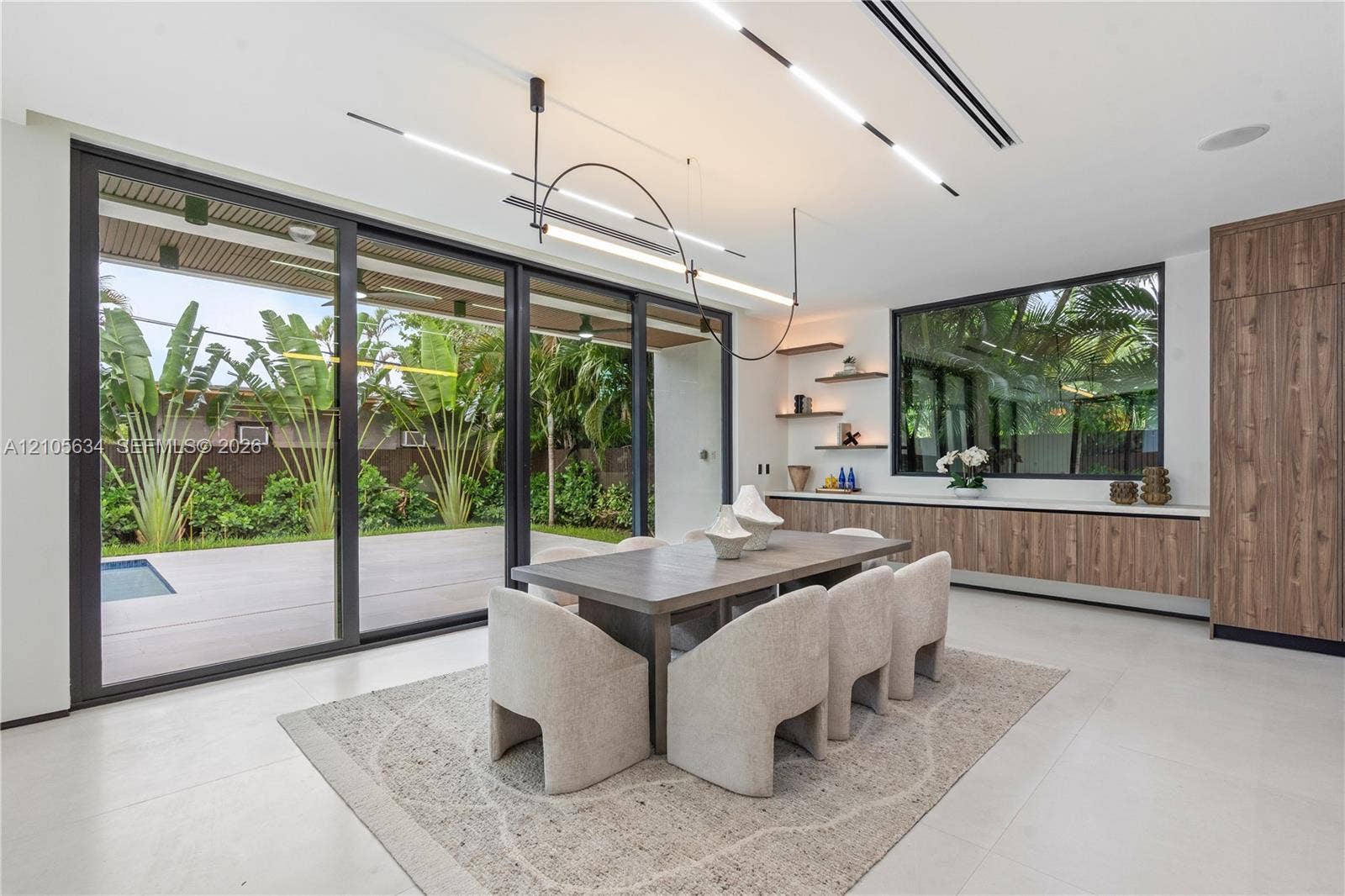 623 NE 16th Terrace, Fort Lauderdale, FL 33304 Large-scale sliding glass doors, contemporary linear LED lighting, custom wood-finish cabinetry, floating wall shelves, and expansive smooth-finish flooring
