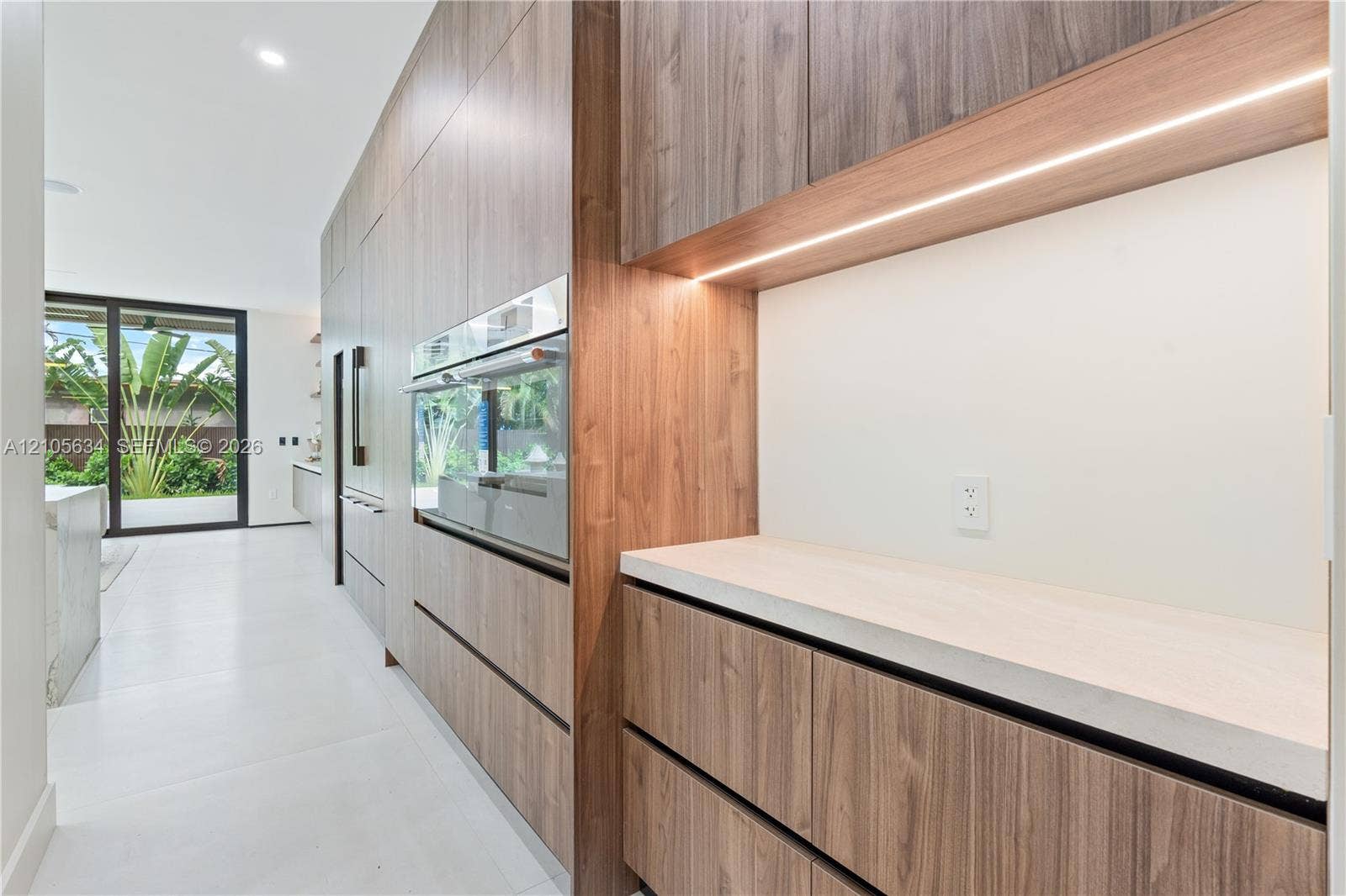 623 NE 16th Terrace, Fort Lauderdale, FL 33304 Full-height wood-finish cabinetry featuring integrated appliances, minimalist hardware, quartz countertops, and built-in under-cabinet LED lighting