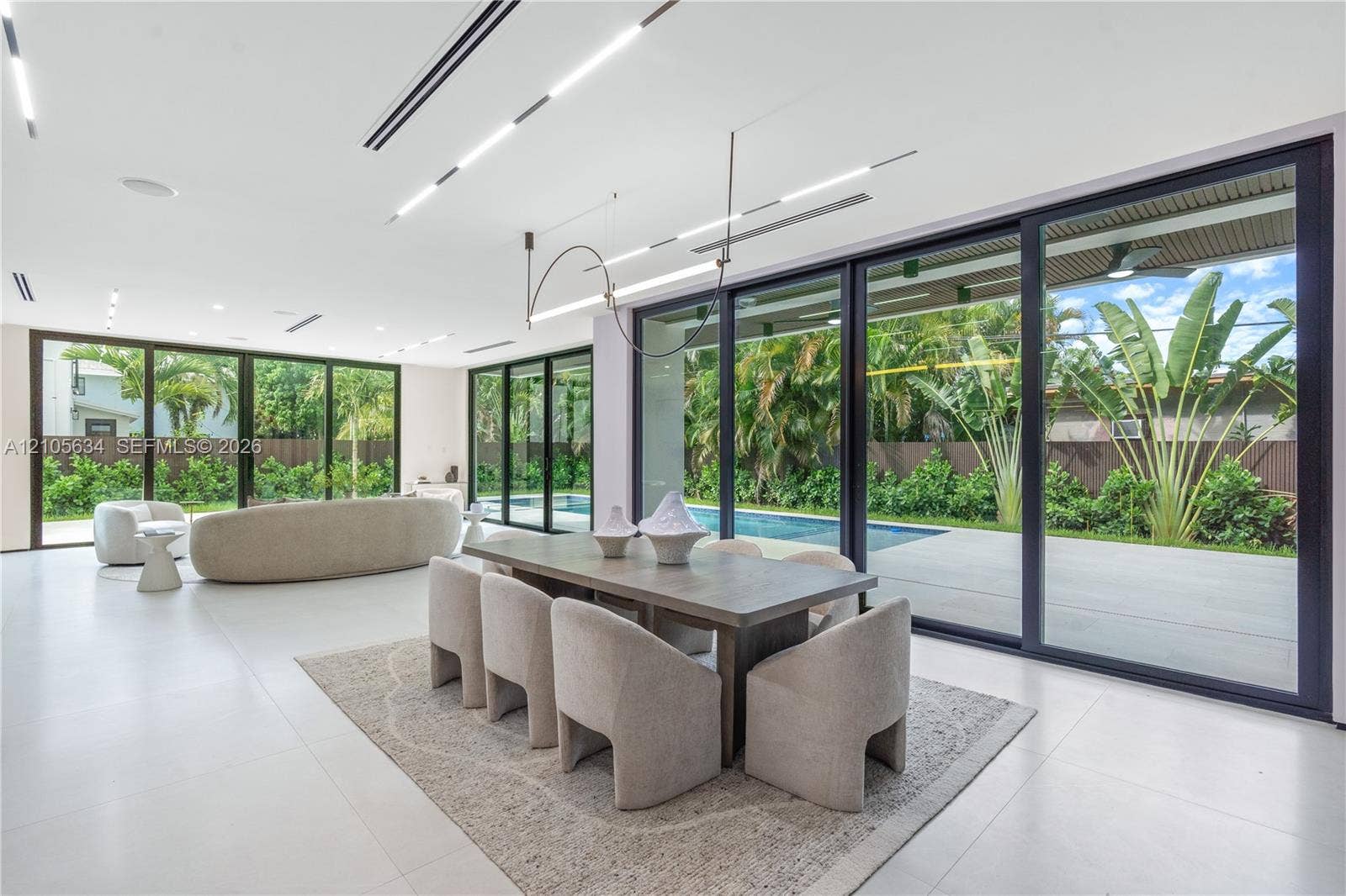 623 NE 16th Terrace, Fort Lauderdale, FL 33304 Open-concept interior featuring large-format tile flooring, recessed linear lighting, and floor-to-ceiling sliding glass doors