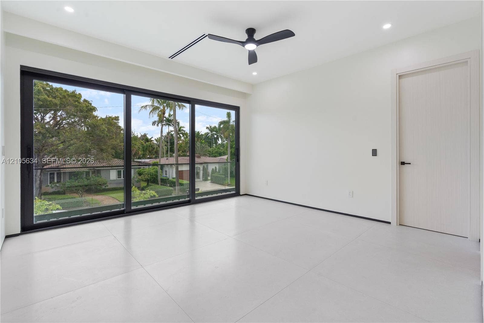 623 NE 16th Terrace, Fort Lauderdale, FL 33304 Floor-to-ceiling sliding glass doors with black frames, large-format tile flooring, recessed lighting, matte black ceiling fan, and solid-core interior door