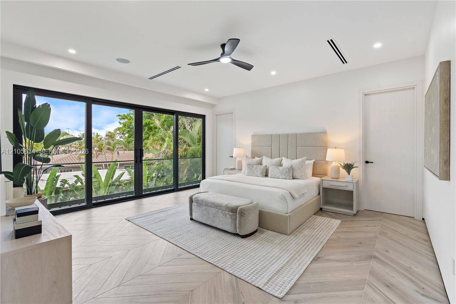 623 NE 16th Terrace, Fort Lauderdale, FL 33304 Interior space featuring chevron-patterned wood-finish flooring, floor-to-ceiling multi-panel sliding glass doors, recessed lighting, and a modern black ceiling fan