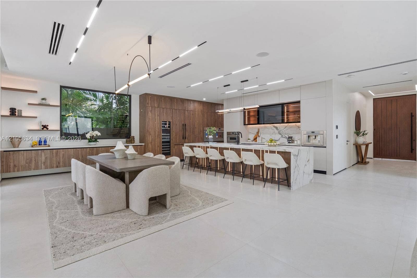 623 NE 16th Terrace, Fort Lauderdale, FL 33304 Open-concept kitchen featuring a waterfall-edge stone island, built-in panel-ready appliances, wood-finish cabinetry, linear recessed ceiling lighting, and porcelain tile flooring