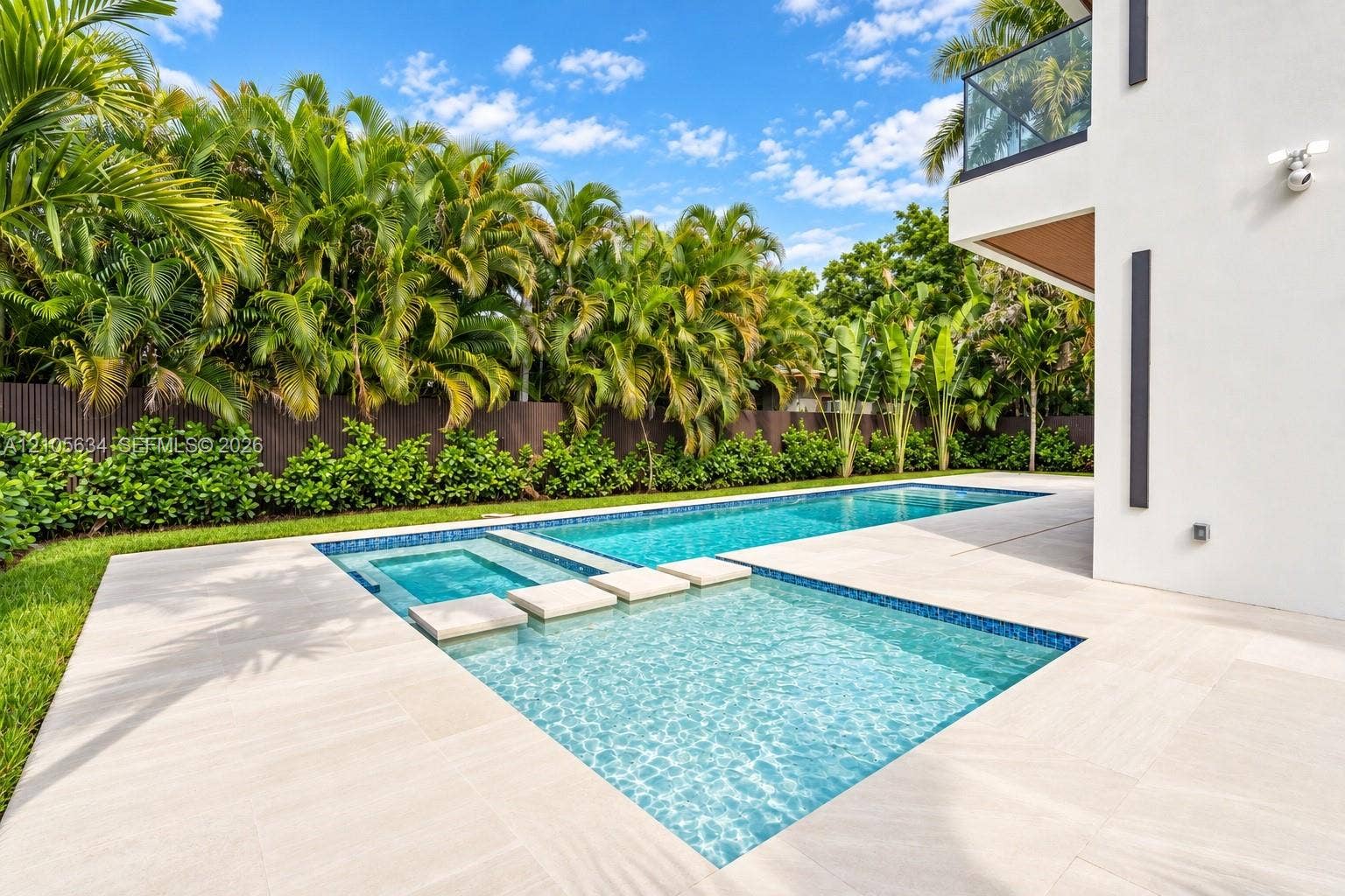 623 NE 16th Terrace, Fort Lauderdale, FL 33304 In-ground swimming pool with an integrated spa, featuring stone-style paver decking, decorative concrete stepping stones, and surrounding lush landscaping