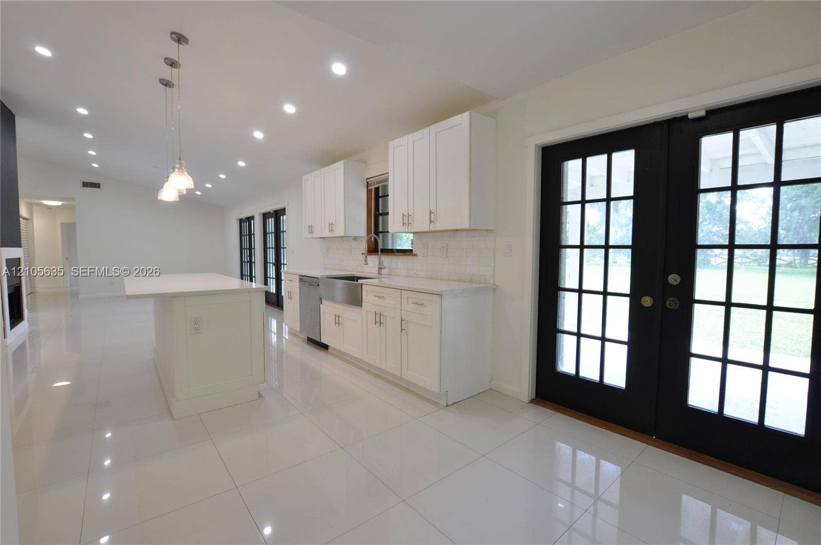 16760 SW 280th Street, Homestead, FL 33031 Kitchen featuring white cabinetry, an island with stone-surface countertop, stainless steel farmhouse-style sink, recessed lighting, and black-framed French doors