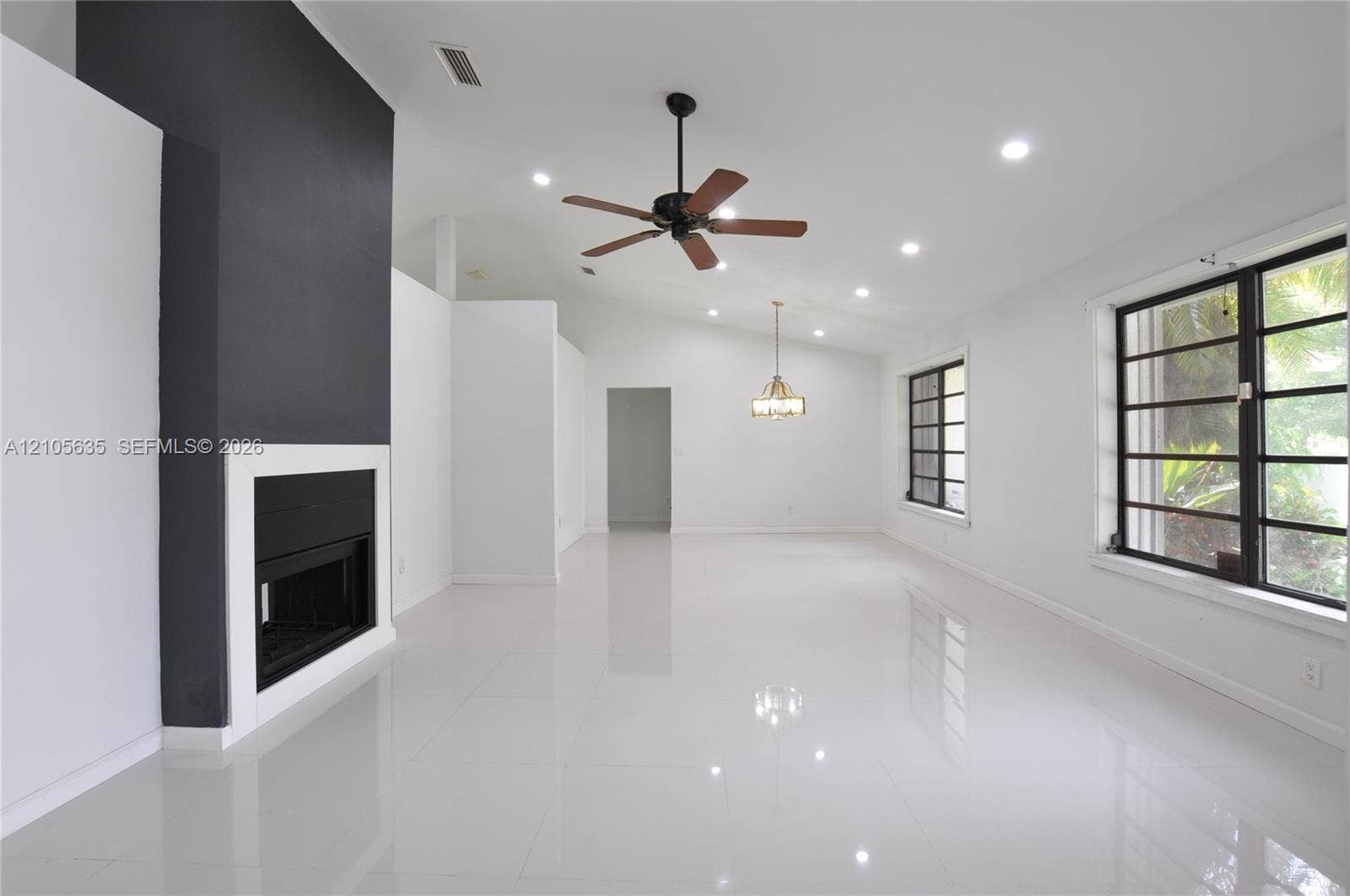 16760 SW 280th Street, Homestead, FL 33031 Living area featuring high vaulted ceilings, large-format polished tile flooring, a floor-to-ceiling accent fireplace, recessed lighting, and a multi-pane grid window system