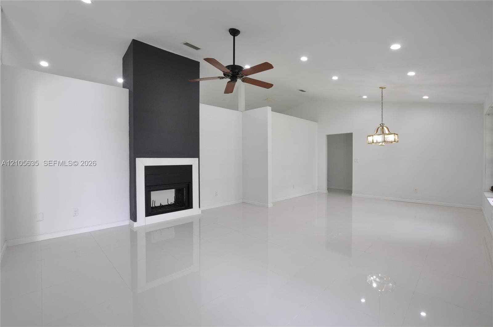 16760 SW 280th Street, Homestead, FL 33031 High-gloss tile flooring, vaulted ceilings, focal point fireplace with dark surround, recessed lighting, and multi-arm chandelier