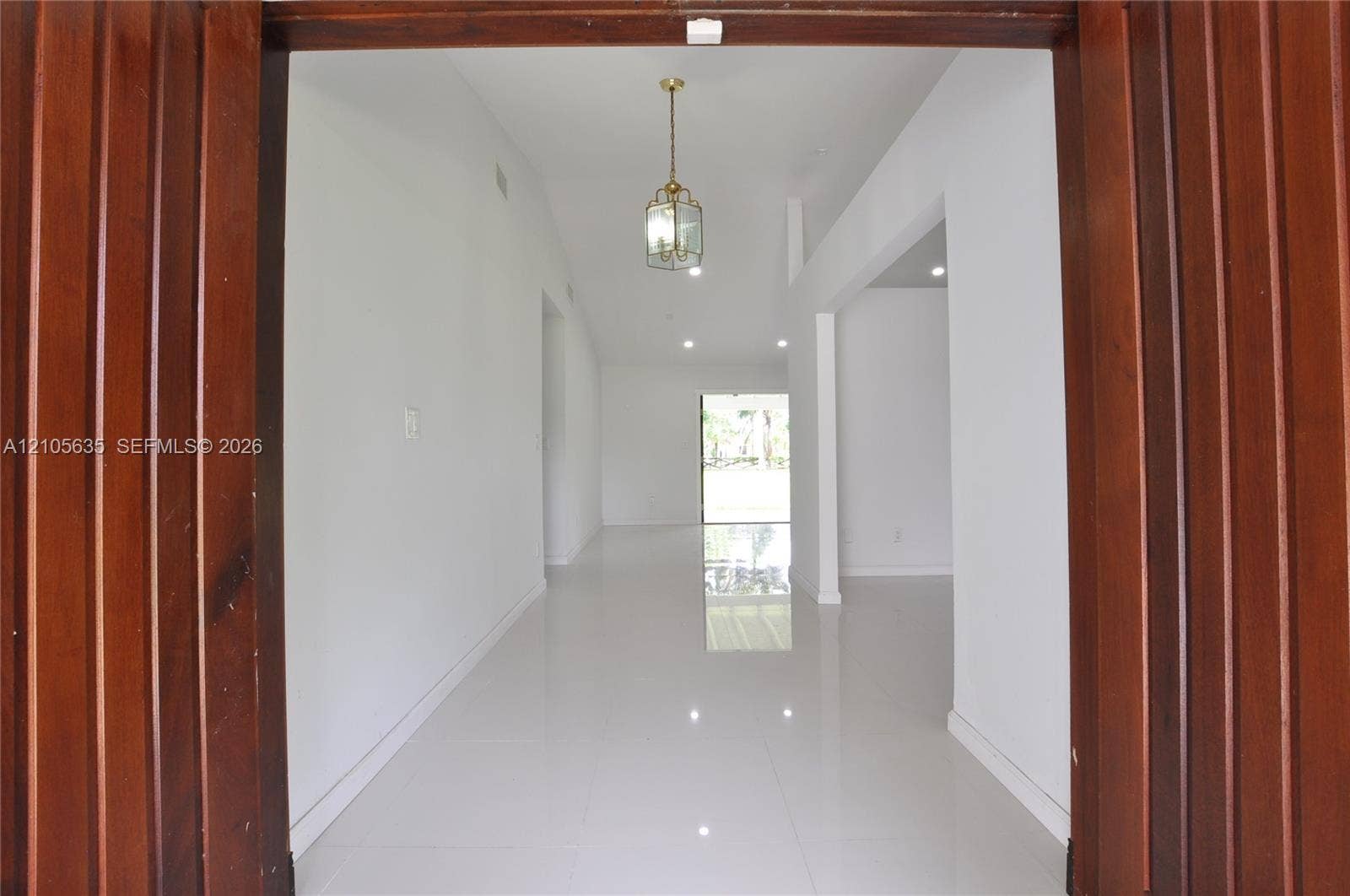16760 SW 280th Street, Homestead, FL 33031 Entryway featuring vertical wood-paneled door trim, high ceilings, polished tile flooring, and a decorative pendant light fixture