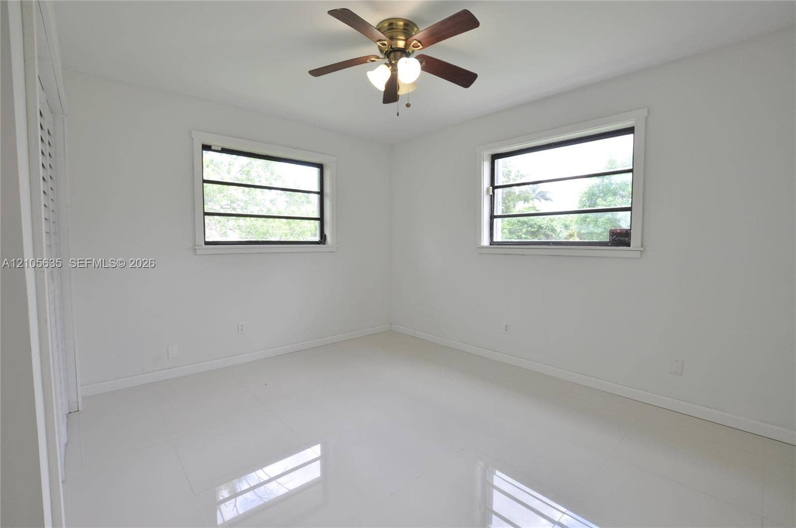 16760 SW 280th Street, Homestead, FL 33031 Neutral interior featuring large-format tile flooring, dual windows, a ceiling fan with integrated lighting, and louvered closet doors
