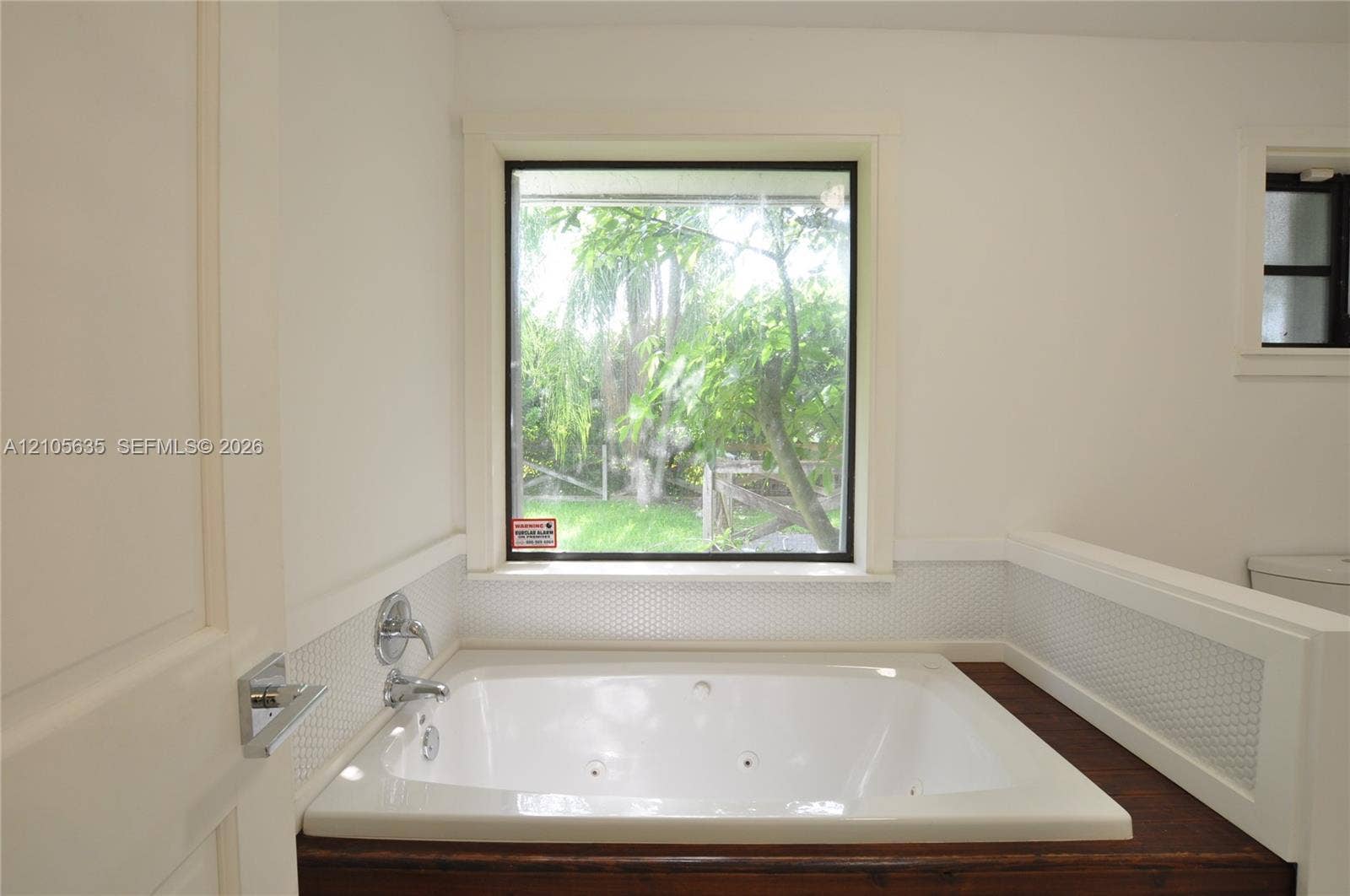 16760 SW 280th Street, Homestead, FL 33031 Jetted soaking tub featuring a wood-finish surround, white penny tile wainscoting, and a large exterior window