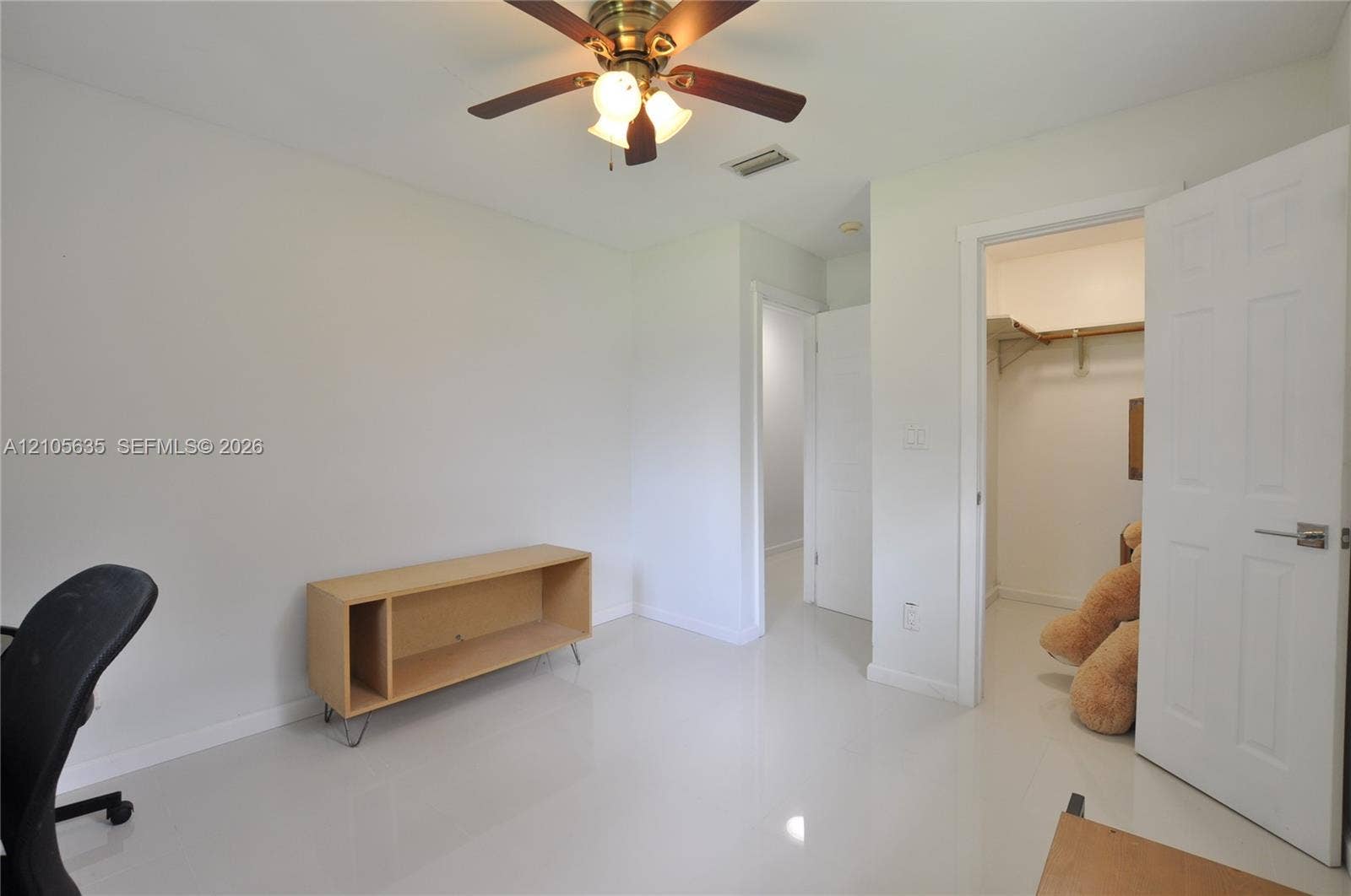 16760 SW 280th Street, Homestead, FL 33031 Room featuring glossy tile flooring, a six-panel door, walk-in closet with built-in shelving, and a ceiling fan with integrated lighting