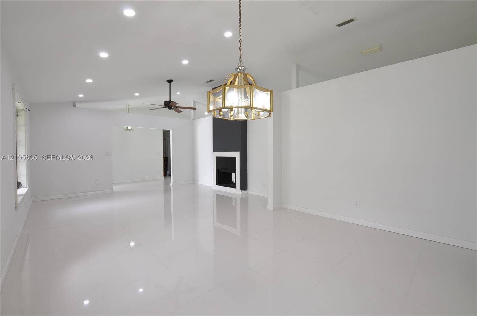16760 SW 280th Street, Homestead, FL 33031 Interior space featuring polished white tile flooring, recessed lighting, a multi-light metallic chandelier, a ceiling fan, and a fireplace with a black surround and white mantel