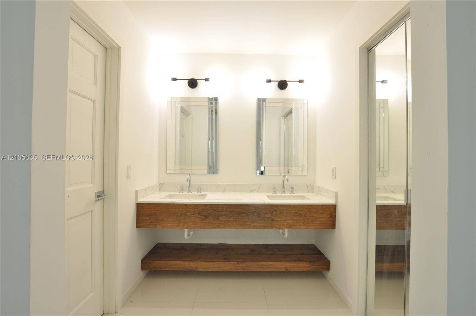 16760 SW 280th Street, Homestead, FL 33031 Floating vanity with a wood-finish frame, stone countertop, dual undermount sinks, wall-mounted light fixtures, and rectangular mirrors