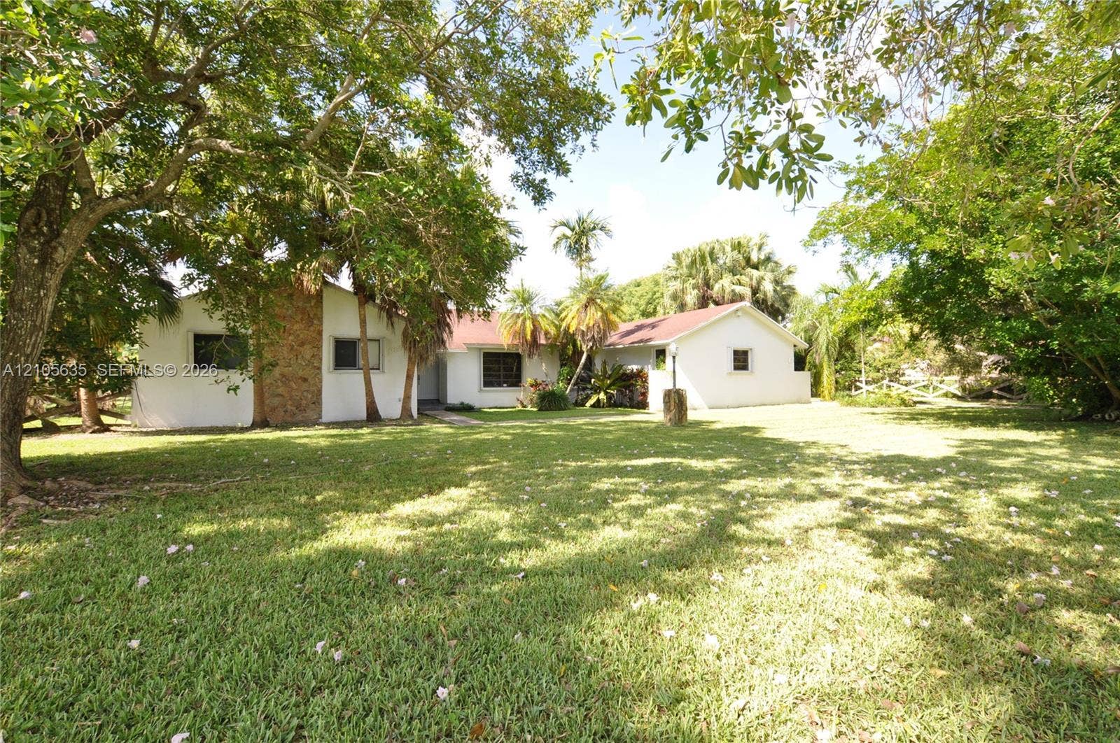 16760 SW 280th Street, Homestead, FL 33031 Expansive grounds featuring mature shade trees, a stone-accented facade, and a low-pitched roofline