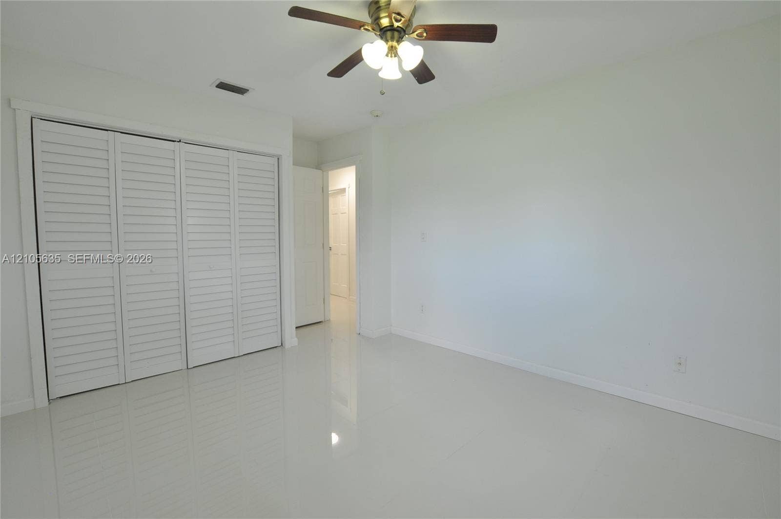 16760 SW 280th Street, Homestead, FL 33031 Neutral-toned tile flooring, white walls, and a multi-panel closet with white louvered doors, accented by a central ceiling fan with integrated lighting