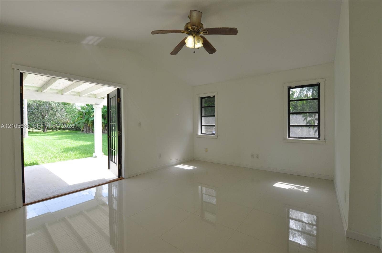 16760 SW 280th Street, Homestead, FL 33031 Room featuring large-format tile flooring, vaulted ceilings, a central ceiling fan, and black-framed double doors opening to a covered patio