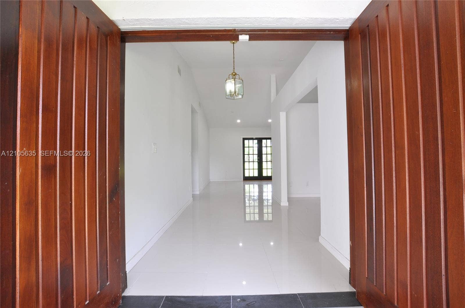 16760 SW 280th Street, Homestead, FL 33031 Double wood-paneled entry doors featuring polished tile flooring, white walls, and a decorative pendant light fixture