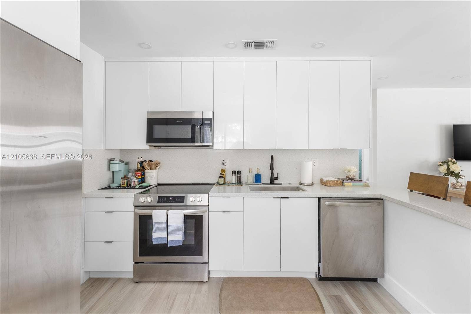 1429 NW 10th Street, #1, Dania, Dania Beach, FL 33004 Kitchen featuring flat-panel white cabinetry, stone-finish countertops, stainless steel appliances, matte black faucet, and wood-finish flooring