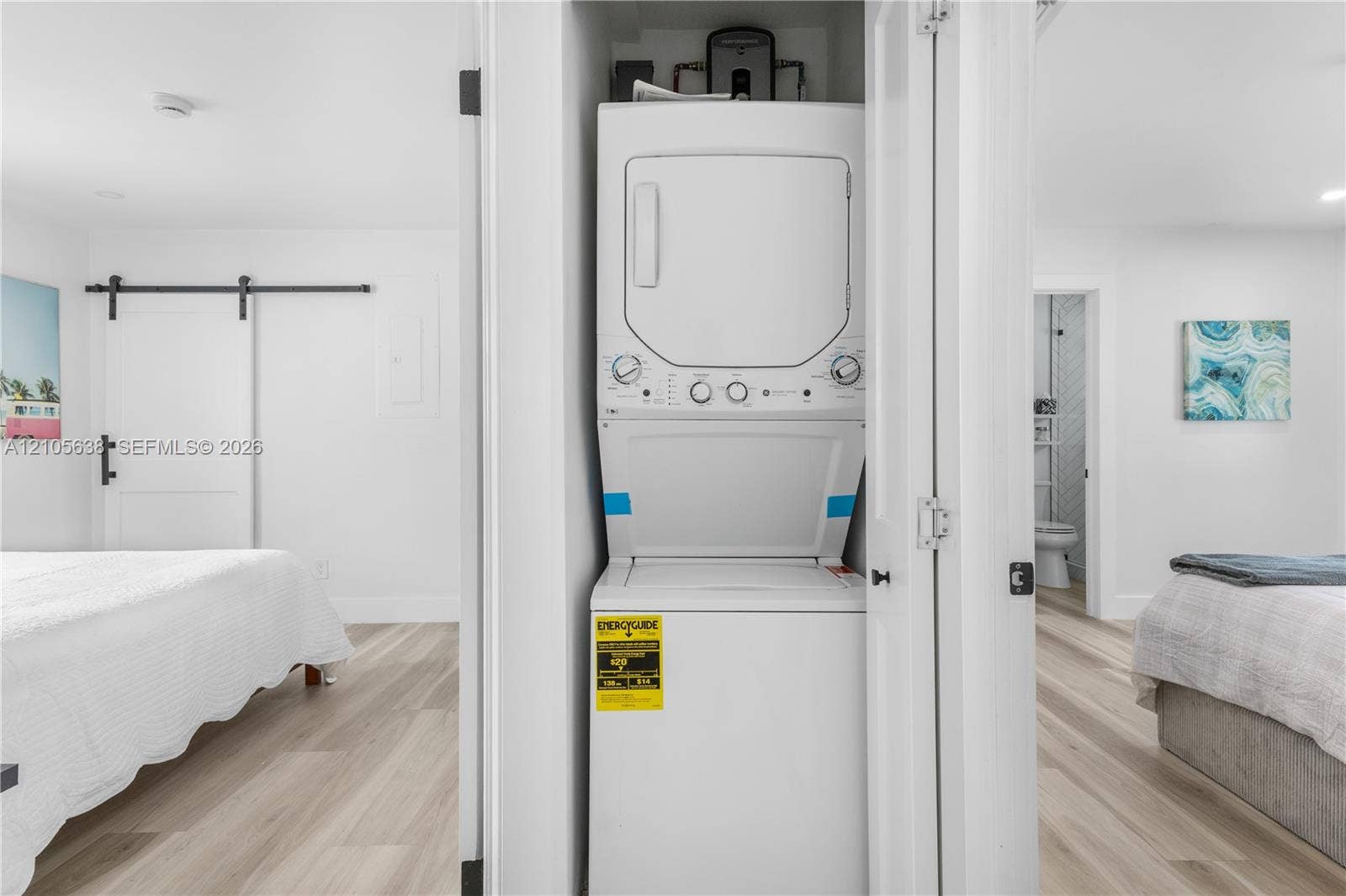 1429 NW 10th Street, #1, Dania, Dania Beach, FL 33004 Built-in stacked laundry unit with bi-fold closet doors, white walls, and wood-finish flooring