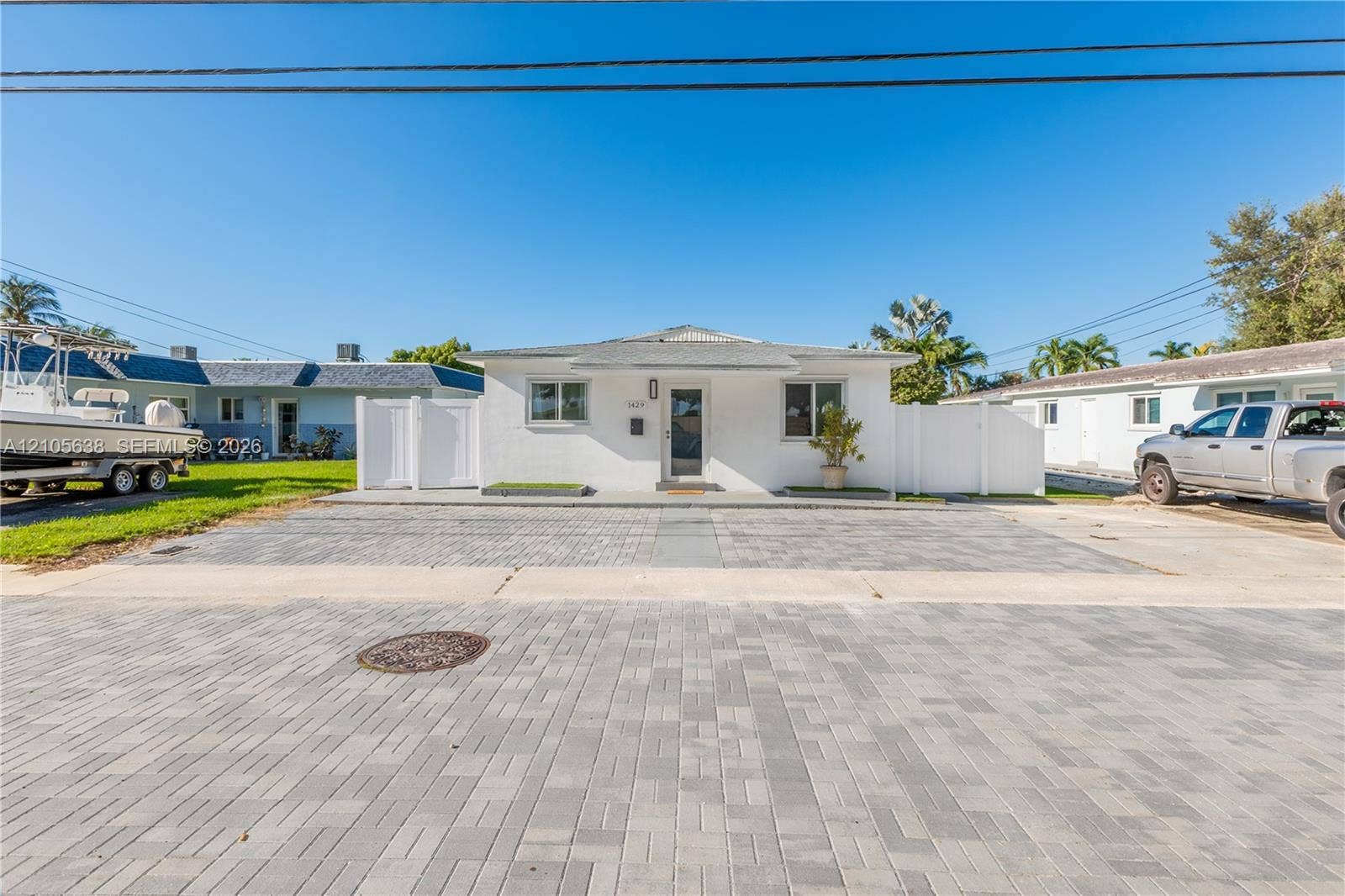 1429 NW 10th Street, #1, Dania, Dania Beach, FL 33004 Single-story exterior featuring white stucco siding, a paved brick driveway, and integrated white privacy fencing