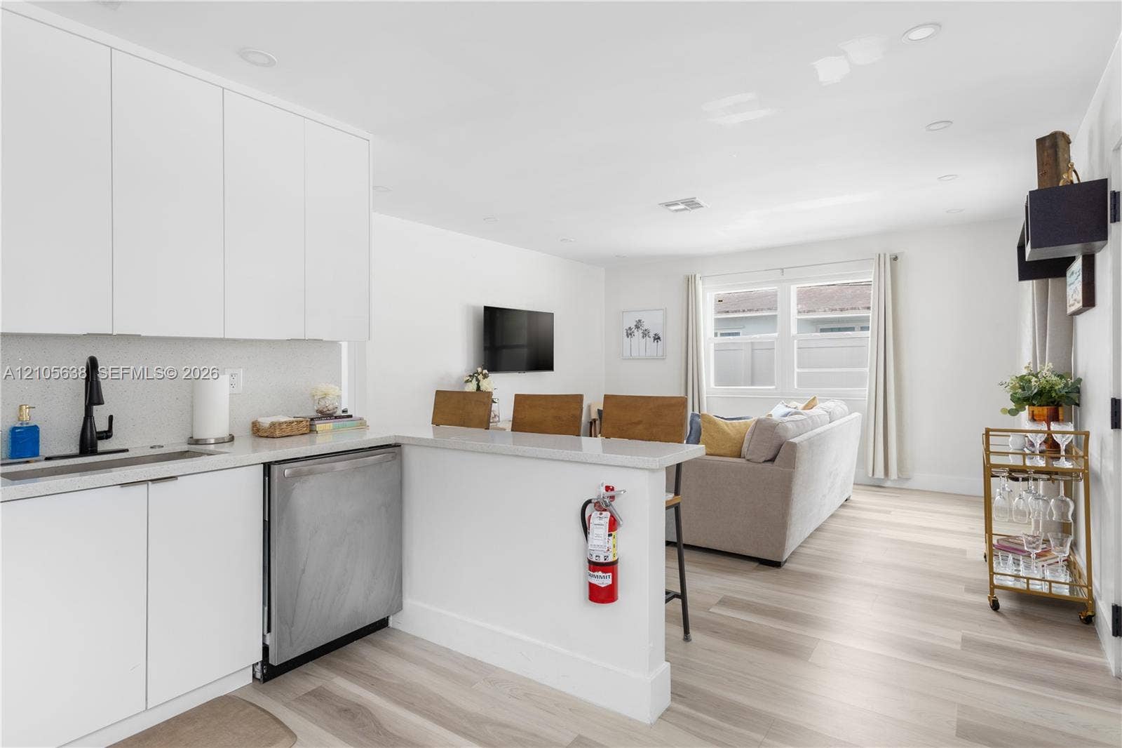 1429 NW 10th Street, #1, Dania, Dania Beach, FL 33004 Modern kitchen featuring sleek white cabinetry, a light-toned countertop, a built-in stainless steel dishwasher, a matte black faucet, and wood-finish flooring