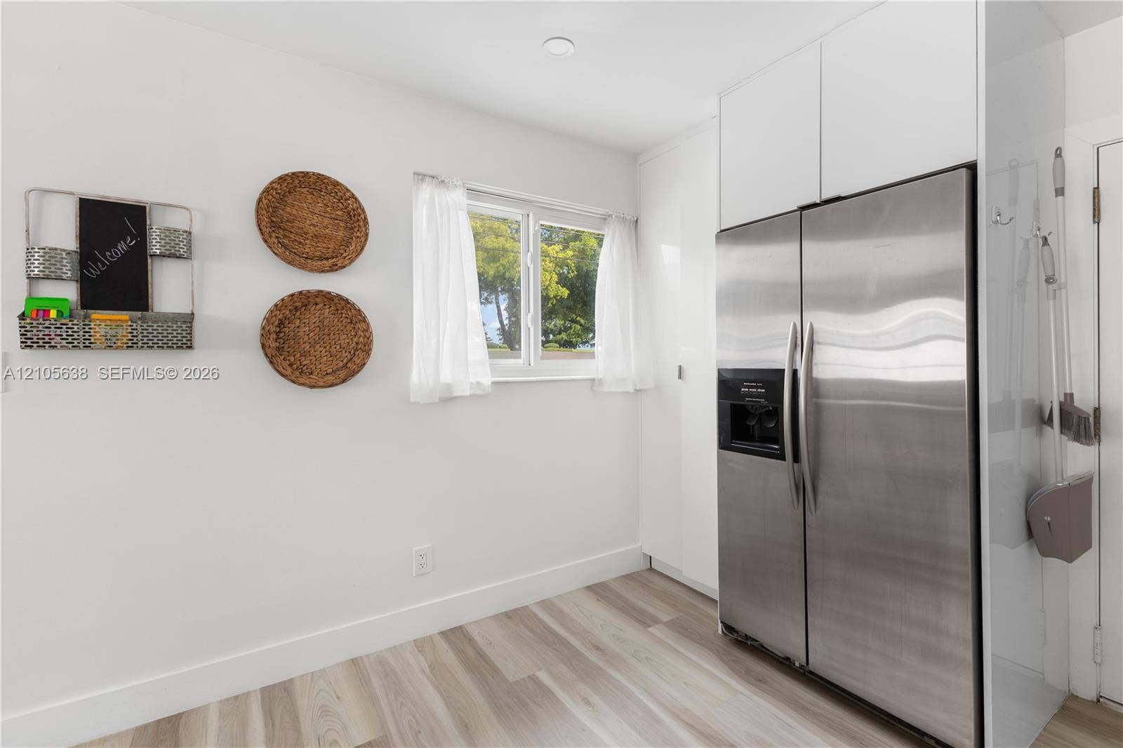 1429 NW 10th Street, #1, Dania, Dania Beach, FL 33004 Stainless steel side-by-side refrigerator, white full-height cabinetry, and wood-finish flooring