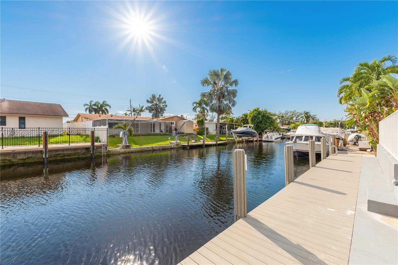 1429 NW 10th Street, #1, Dania, Dania Beach, FL 33004 Waterfront property featuring a private canal-side dock, concrete bulkhead, and established palm trees