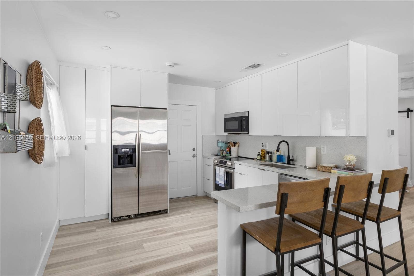 1429 NW 10th Street, #1, Dania, Dania Beach, FL 33004 Kitchen featuring white flat-panel cabinetry, stainless steel appliances, quartz countertops, a matte black faucet, and wood-finish flooring
