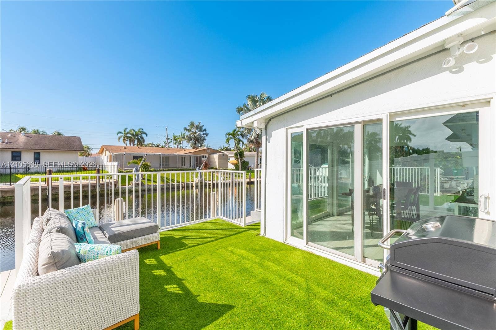 1429 NW 10th Street, #1, Dania, Dania Beach, FL 33004 Waterfront patio featuring synthetic turf surfacing, white metal perimeter railings, and sliding glass door access