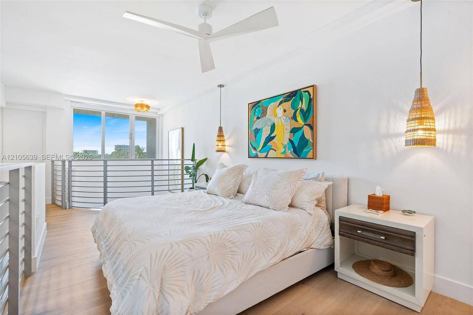 Wood-finish flooring, white three-blade ceiling fan, metal stair railing, and dual woven-shade pendant lights