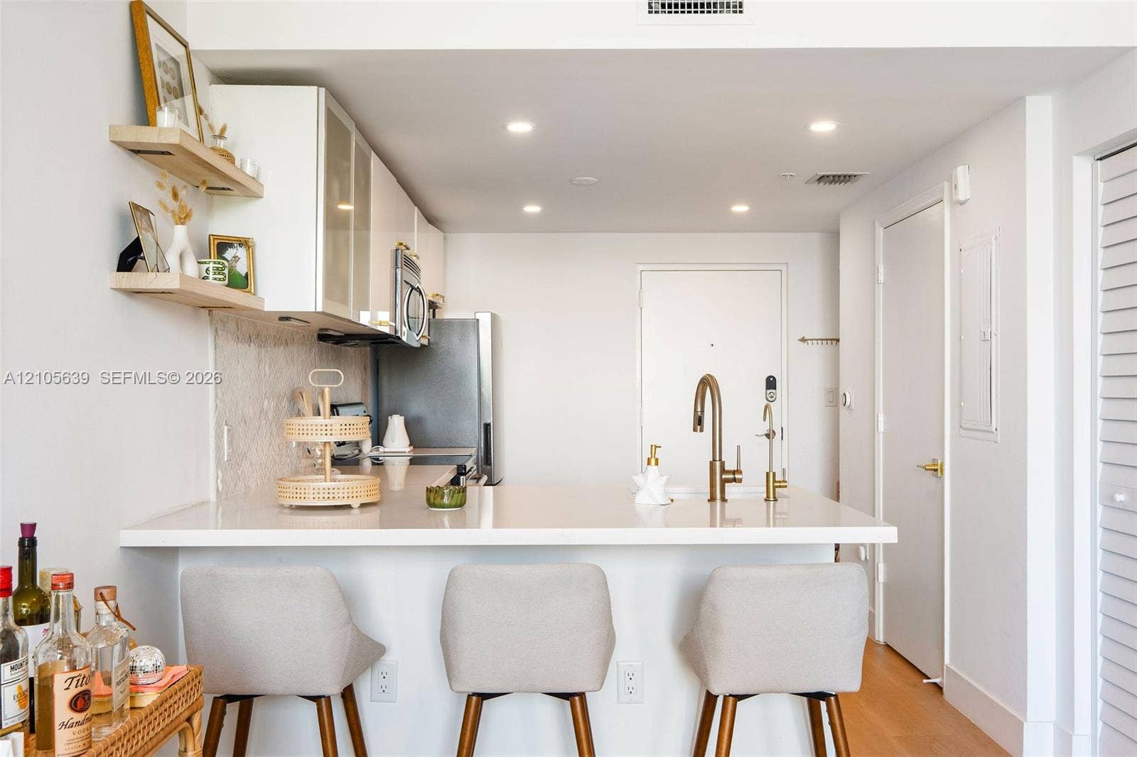 Kitchen featuring quartz countertops, white cabinetry, recessed lighting, wood-finish flooring, and floating wall shelves