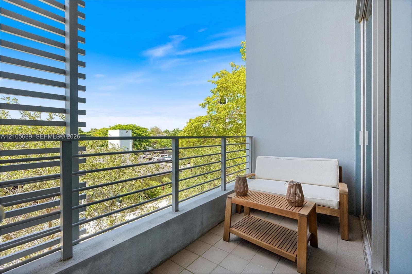 Private balcony featuring a concrete base, metal horizontal slat privacy screen, and powder-coated metal railing
