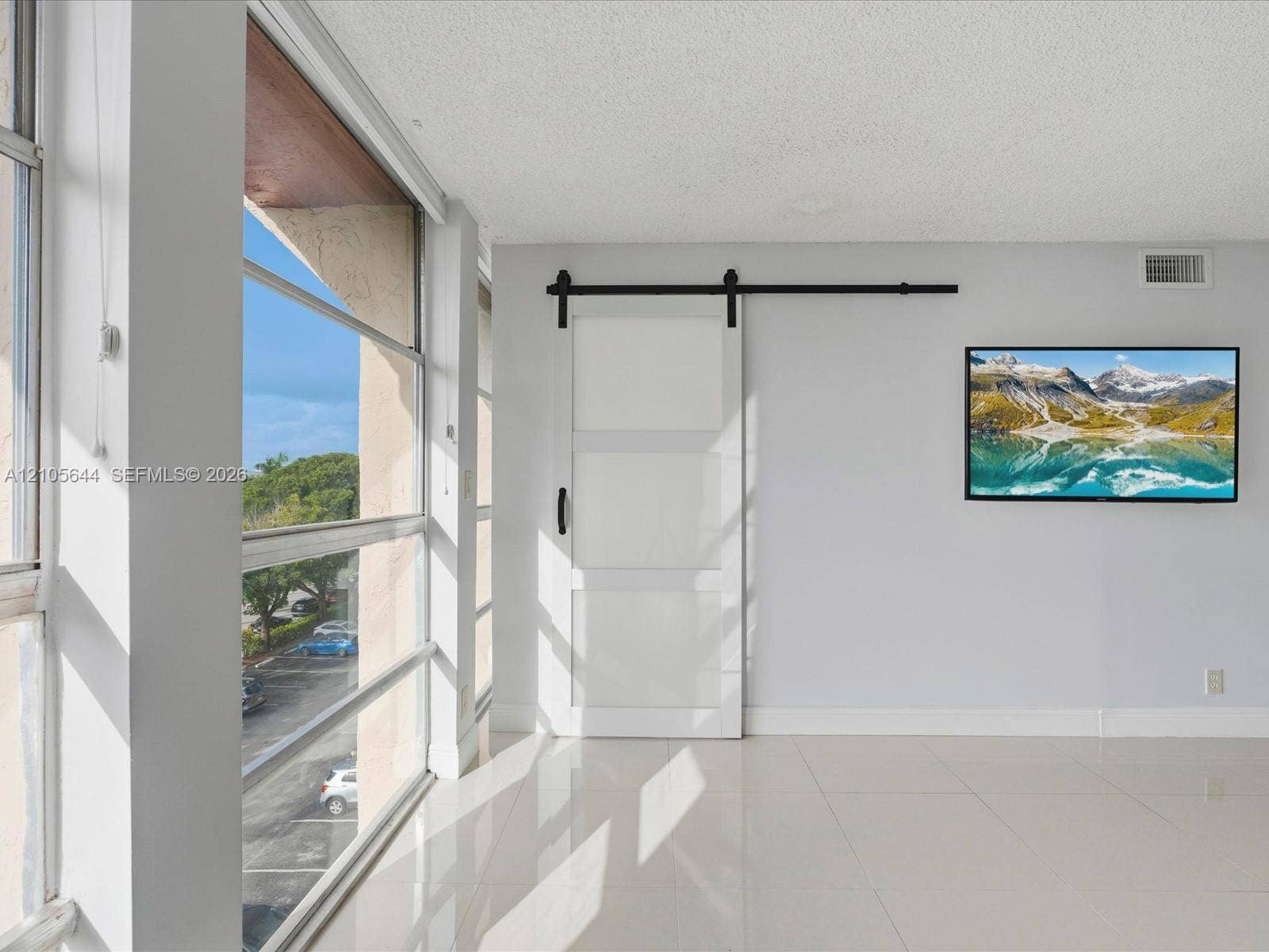 2101 Atlantic Shores Boulevard, #502, Hallandale Beach, Hallandale Beach, FL 33009 Large floor-to-ceiling windows, white tile flooring, and a white sliding barn door featuring matte black hardware